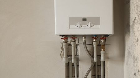 Installation of home gas heating boiler with red taps close up